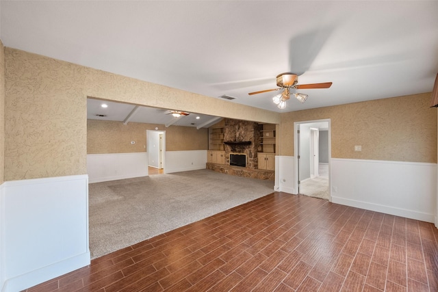 unfurnished living room featuring wood-type flooring, built in shelves, a fireplace, and ceiling fan