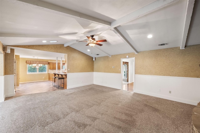 unfurnished living room featuring light colored carpet, lofted ceiling with beams, and ceiling fan