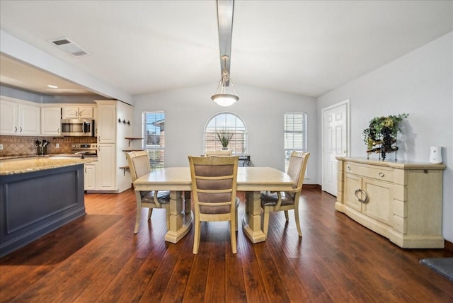 dining space featuring lofted ceiling with beams and dark hardwood / wood-style floors