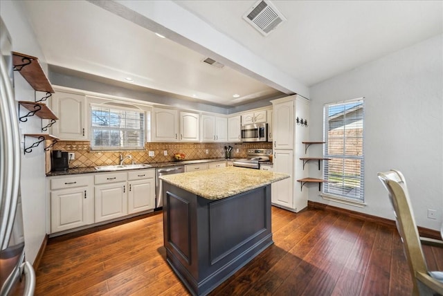 kitchen featuring white cabinetry, sink, stainless steel appliances, and dark stone countertops