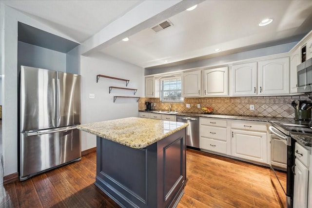 kitchen with hardwood / wood-style flooring, appliances with stainless steel finishes, a kitchen island, and white cabinets