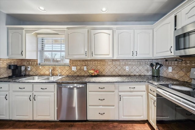 kitchen featuring stainless steel appliances, white cabinetry, sink, and dark stone counters