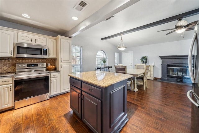 kitchen featuring appliances with stainless steel finishes, decorative light fixtures, tasteful backsplash, dark hardwood / wood-style flooring, and a center island