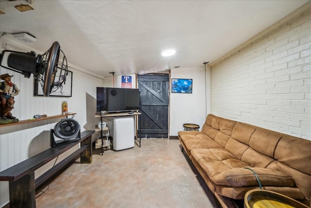 living room featuring brick wall, a barn door, and concrete floors