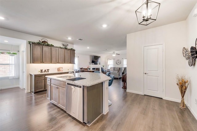 kitchen with dishwasher, open floor plan, decorative light fixtures, a kitchen island with sink, and a sink