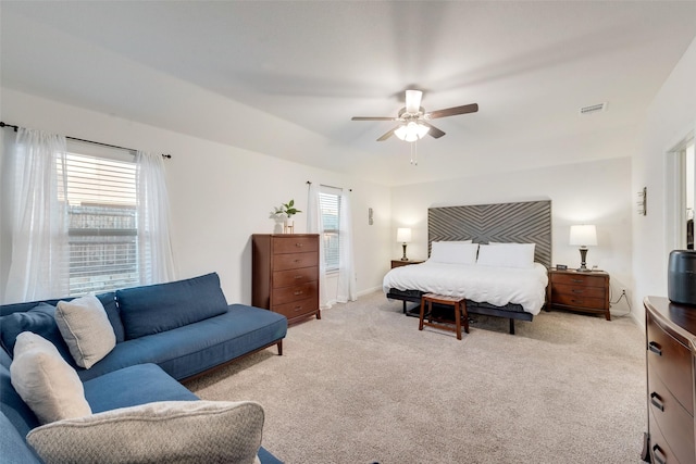 bedroom with light carpet, multiple windows, visible vents, and a ceiling fan