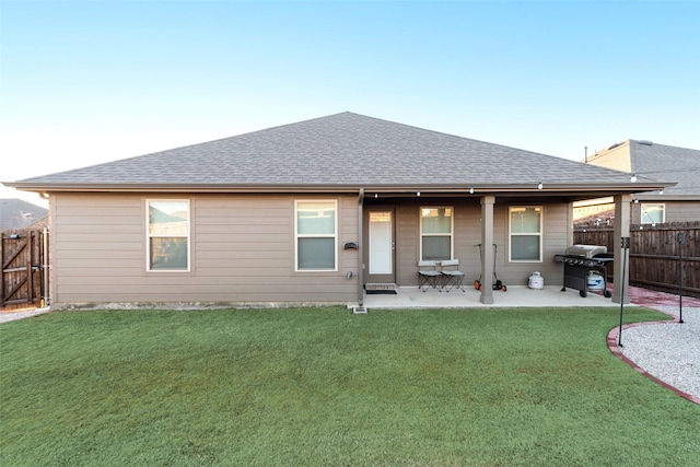 back of house featuring a yard, a patio, a shingled roof, and fence