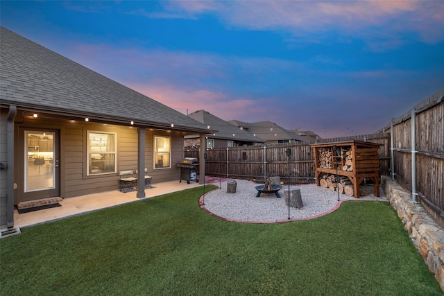 yard at dusk with a fire pit, a patio area, and a fenced backyard