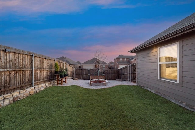 yard at dusk featuring an outdoor fire pit and a fenced backyard