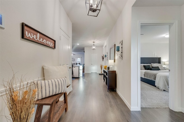 corridor featuring a notable chandelier, baseboards, and wood finished floors