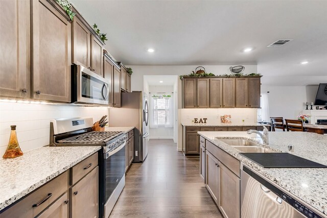 kitchen with light stone countertops, visible vents, stainless steel appliances, and a sink