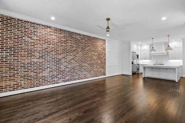 unfurnished living room with sink, ornamental molding, dark hardwood / wood-style floors, and brick wall