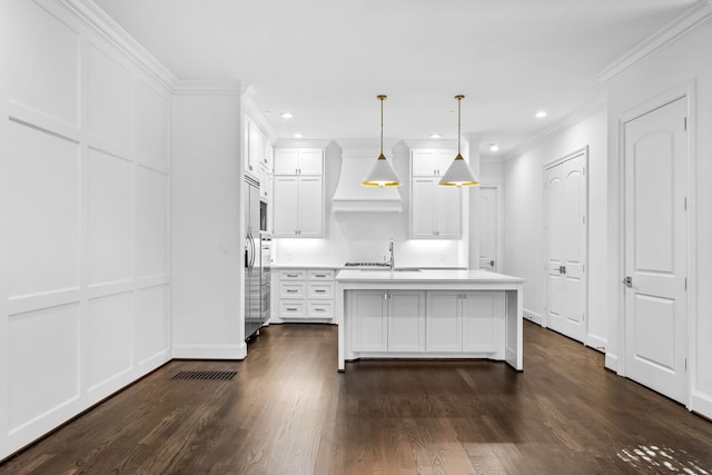 kitchen with pendant lighting, white cabinetry, crown molding, and premium range hood