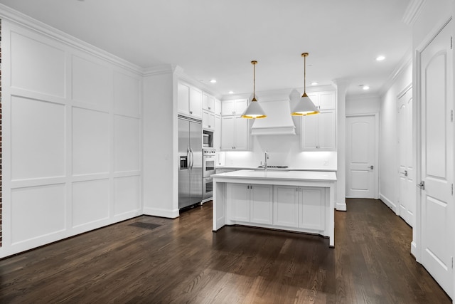 kitchen with decorative light fixtures, white cabinetry, dark hardwood / wood-style flooring, built in appliances, and a center island with sink