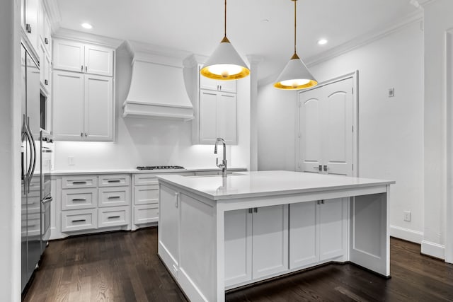 kitchen featuring sink, premium range hood, hanging light fixtures, an island with sink, and white cabinets