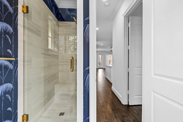 bathroom with hardwood / wood-style floors, crown molding, and a shower with door