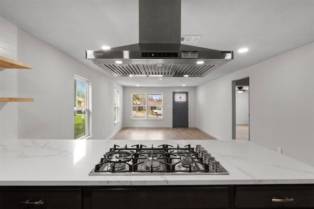 kitchen with light stone counters, open shelves, island exhaust hood, recessed lighting, and stainless steel gas stovetop