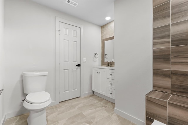 bathroom featuring vanity, toilet, baseboards, and visible vents