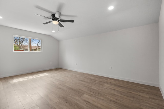 spare room featuring vaulted ceiling, wood finished floors, baseboards, and ceiling fan