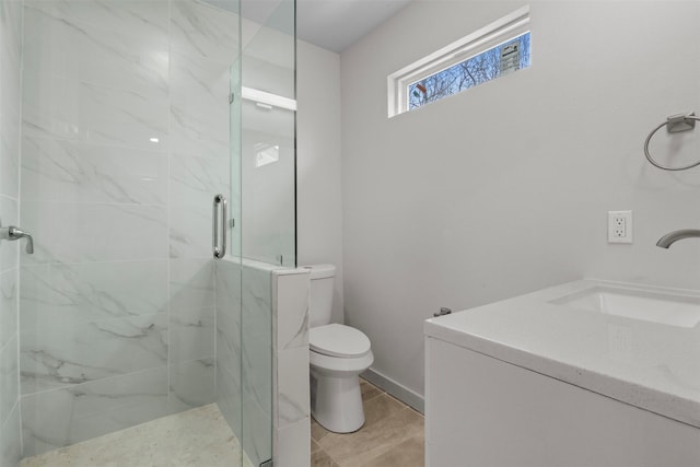 bathroom featuring a marble finish shower, toilet, vanity, and baseboards