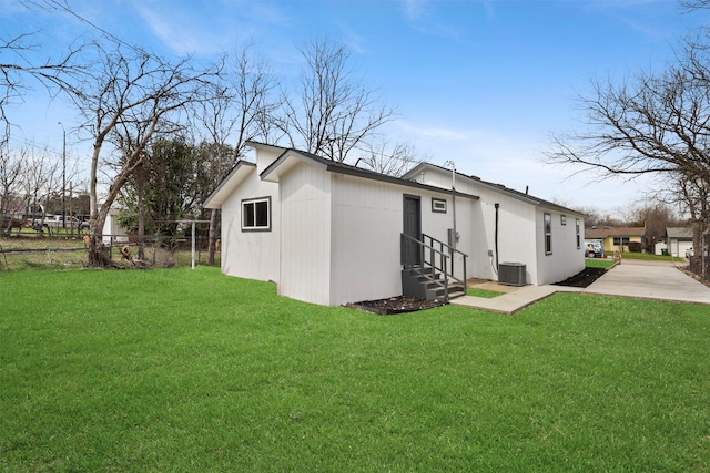 view of side of home with entry steps, a lawn, fence, and central AC