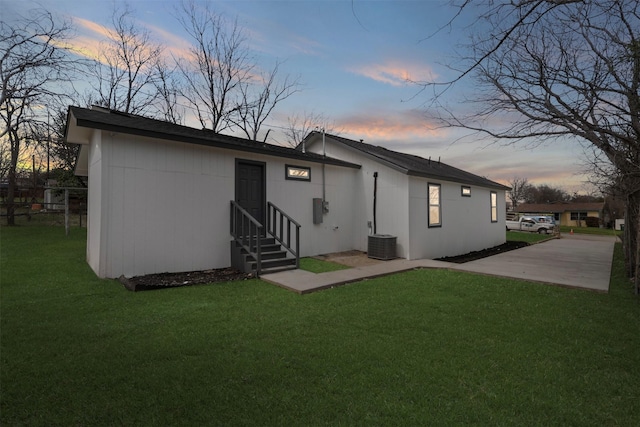 back of property at dusk featuring a lawn, central AC, and entry steps