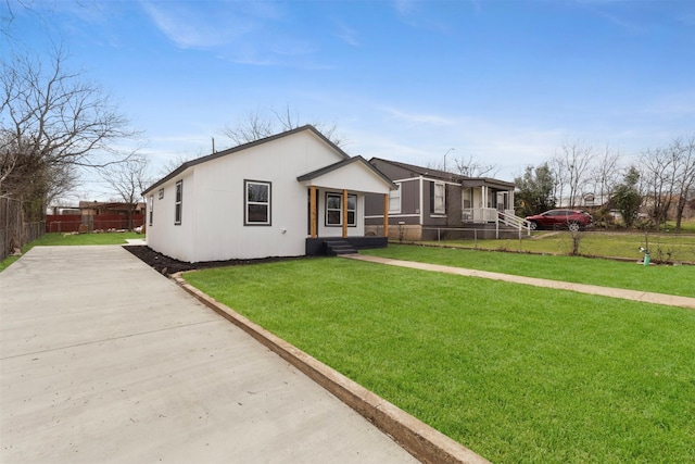 view of front of home with entry steps, a front yard, concrete driveway, and fence