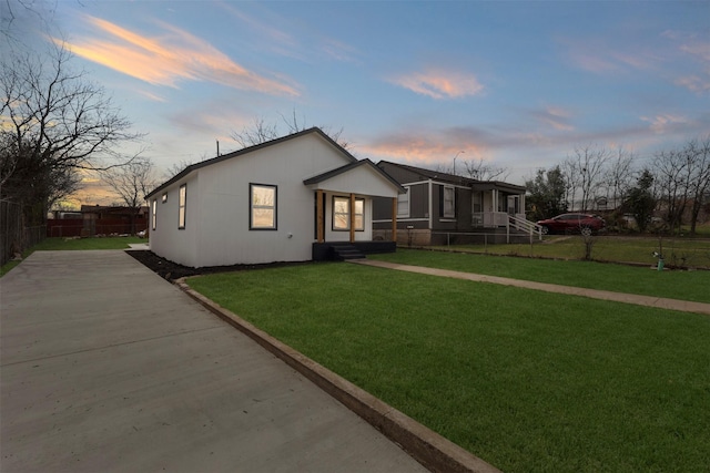 view of front of house with a front lawn, driveway, and fence