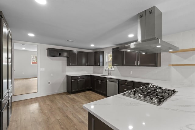 kitchen featuring island exhaust hood, stainless steel appliances, light stone counters, and light wood finished floors