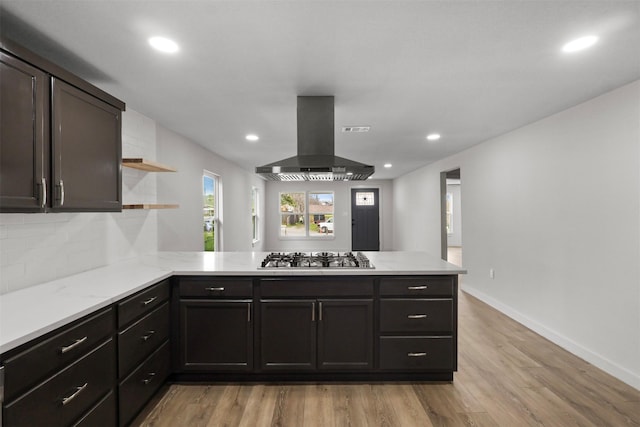 kitchen featuring light wood-type flooring, open shelves, stainless steel gas stovetop, a peninsula, and extractor fan