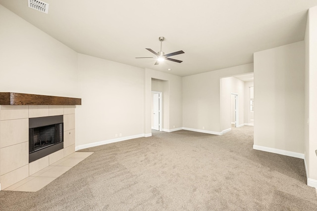 unfurnished living room featuring baseboards, visible vents, a ceiling fan, a tiled fireplace, and light colored carpet