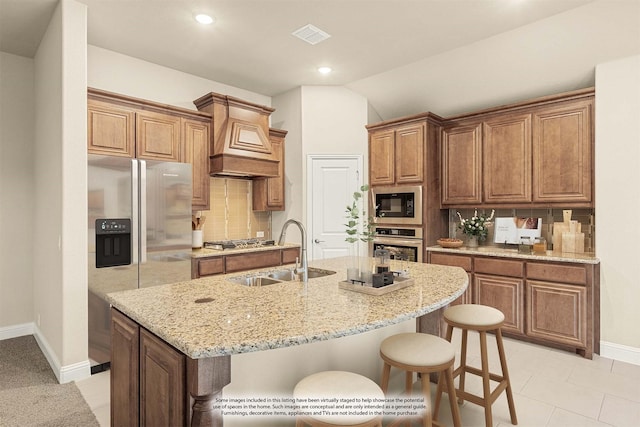 kitchen with stainless steel appliances, a sink, a kitchen breakfast bar, decorative backsplash, and a center island with sink