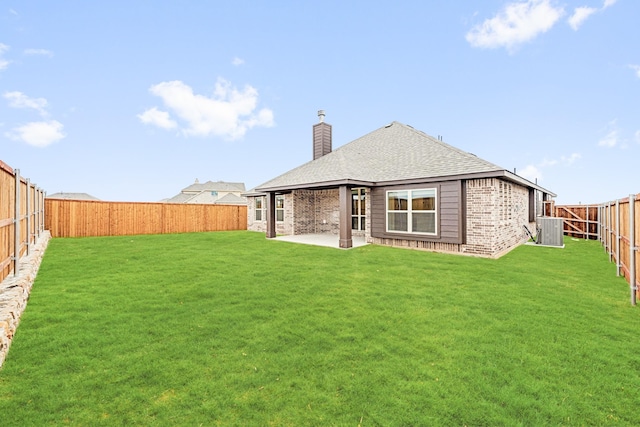 rear view of property with brick siding, a patio, a chimney, a lawn, and central AC