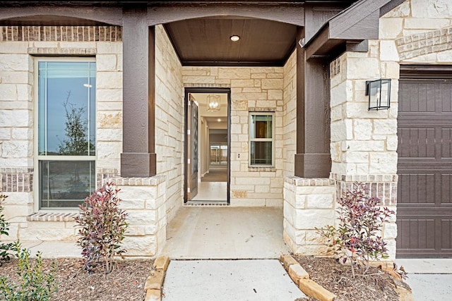 doorway to property featuring a garage and stone siding