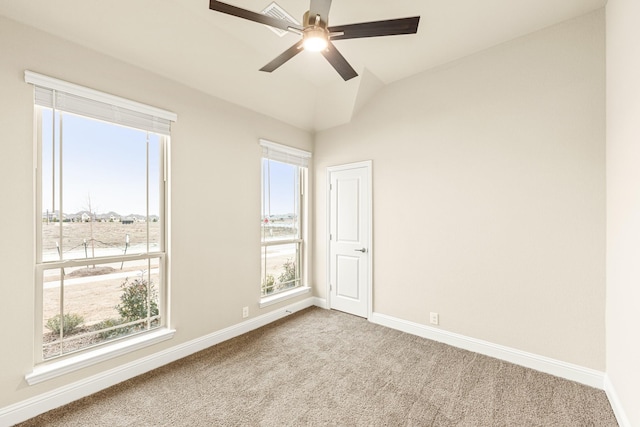 empty room with carpet flooring, a healthy amount of sunlight, vaulted ceiling, and baseboards