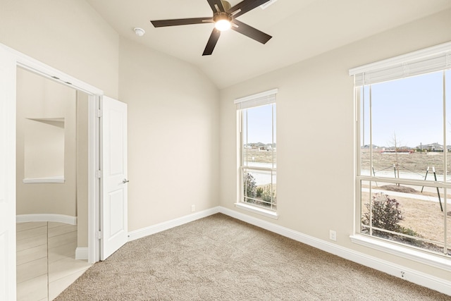 spare room featuring a ceiling fan, baseboards, vaulted ceiling, and carpet flooring