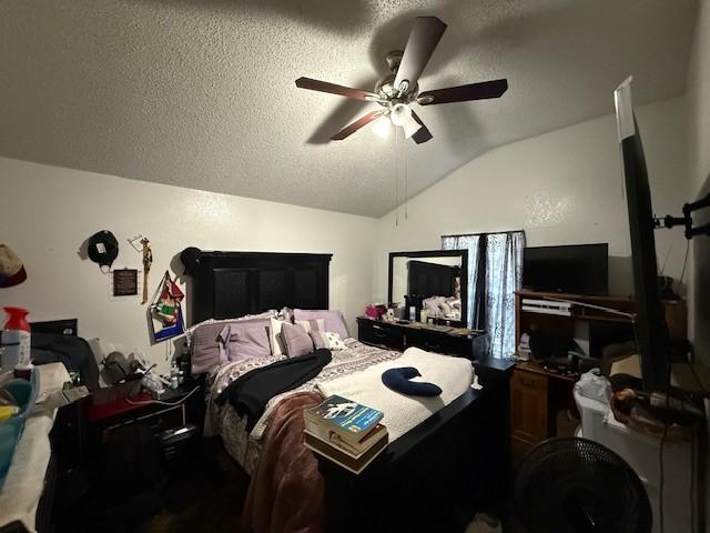 bedroom featuring ceiling fan, vaulted ceiling, and a textured ceiling