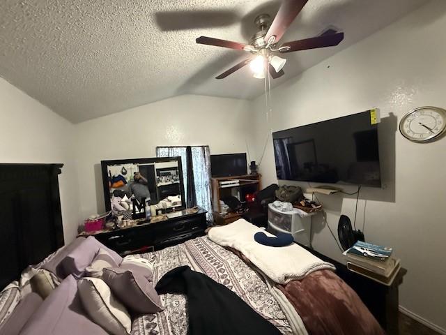 bedroom featuring ceiling fan, lofted ceiling, and a textured ceiling