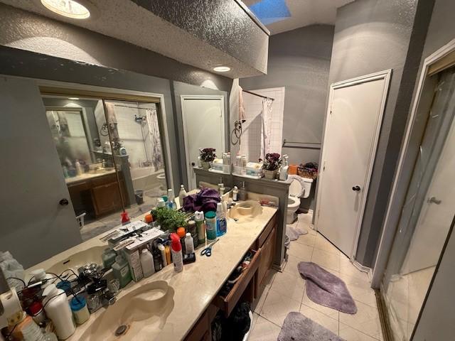 bathroom featuring vanity, tile patterned flooring, toilet, and walk in shower