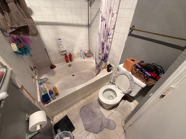 bathroom with shower / bathtub combination with curtain, tile patterned flooring, and toilet