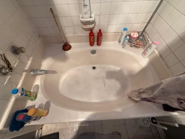 bathroom with a tub to relax in and tile walls