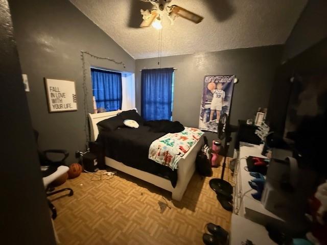 bedroom featuring parquet floors, vaulted ceiling, a textured ceiling, and ceiling fan