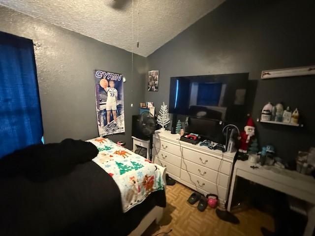 bedroom with parquet flooring, lofted ceiling, and a textured ceiling