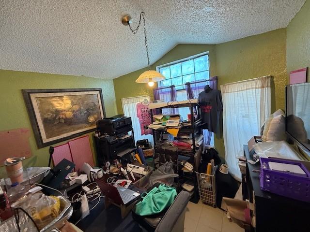 miscellaneous room featuring light tile patterned floors, vaulted ceiling, and a textured ceiling