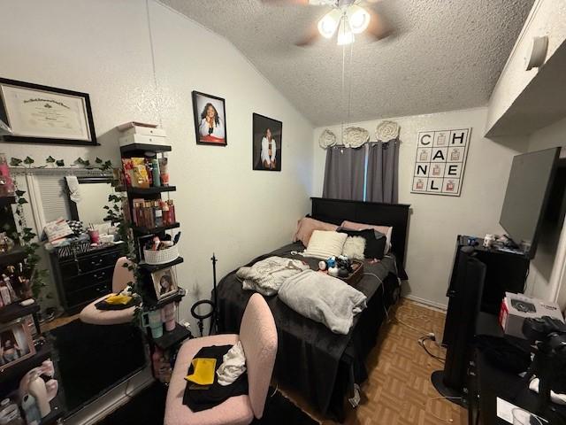 bedroom with lofted ceiling, parquet floors, a textured ceiling, and ceiling fan