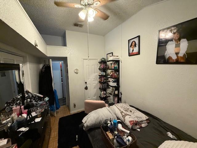 bedroom featuring parquet floors, ceiling fan, lofted ceiling, and a textured ceiling