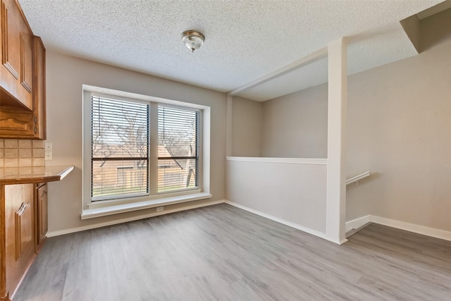 unfurnished dining area with a textured ceiling and light hardwood / wood-style floors