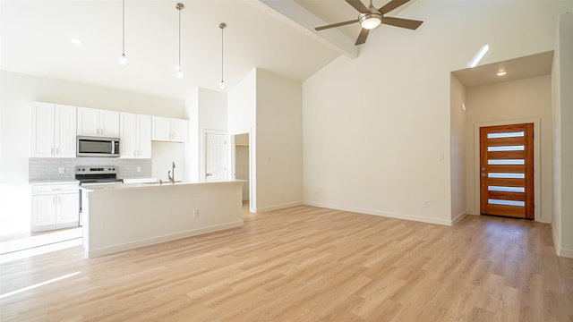 kitchen with a kitchen island with sink, hanging light fixtures, stainless steel appliances, and white cabinets