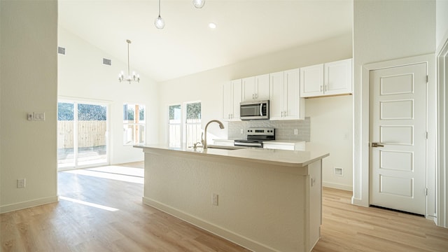 kitchen with sink, decorative light fixtures, an island with sink, stainless steel appliances, and white cabinets