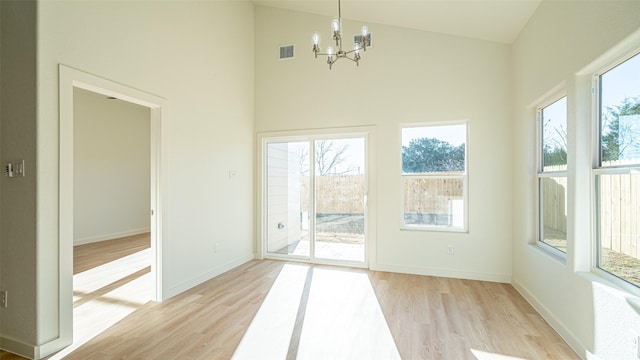 entryway with light hardwood / wood-style flooring, high vaulted ceiling, and a chandelier